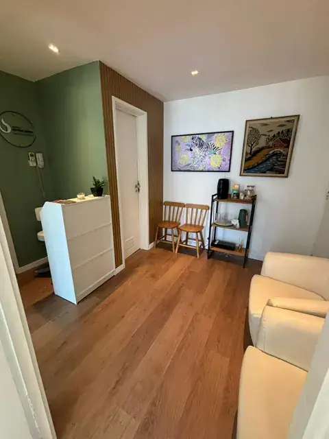 Recepção com parede verde, balcão branco e cadeiras de madeira