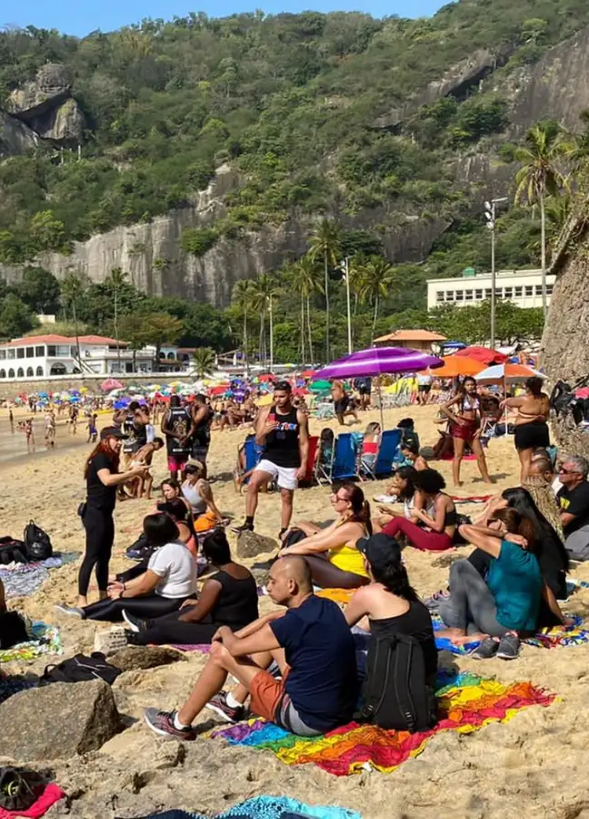 Dinâmica ao ar livre na praia com grupo de participantes sentados na areia, em frente ao morro